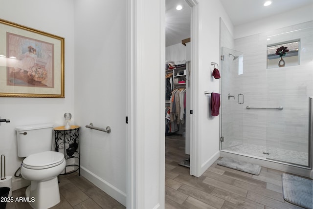 17385 W Sugar Hill Ct, Surprise, AZ 85388 - bathroom with a stall shower, a walk in closet, toilet, baseboards, and wood finished floors