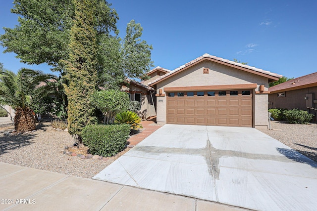 view of front of property with an attached garage, a tile roof, concrete driveway, and stucco siding