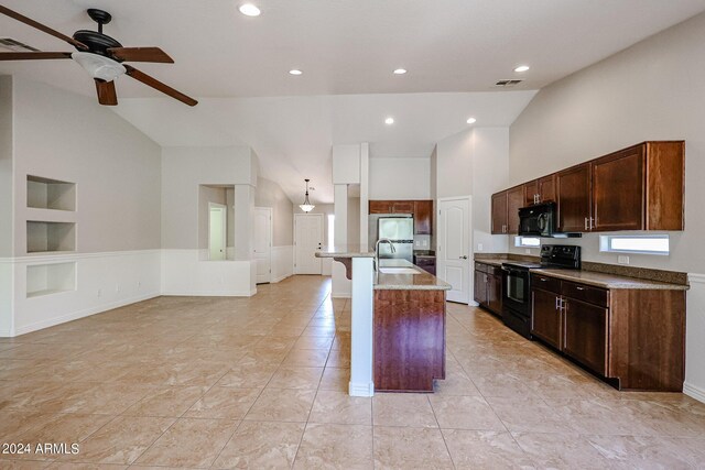 kitchen with a kitchen island with sink, black appliances, light stone counters, sink, and ceiling fan