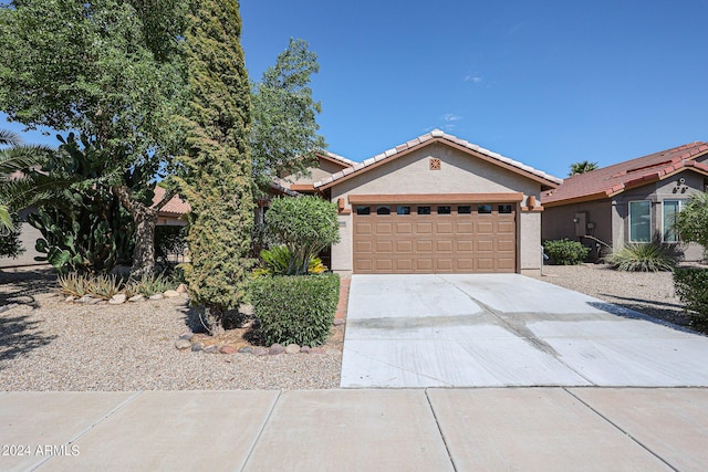 view of front of house featuring concrete driveway, a tiled roof, an attached garage, and stucco siding