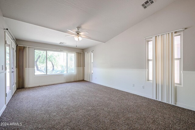 carpeted empty room with lofted ceiling, ceiling fan, and a textured ceiling