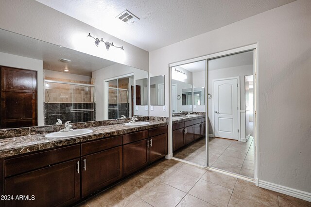 bathroom featuring a textured ceiling, vanity, a shower with shower door, and tile patterned floors