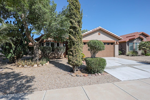 view of front of property featuring driveway, a tiled roof, a garage, and stucco siding