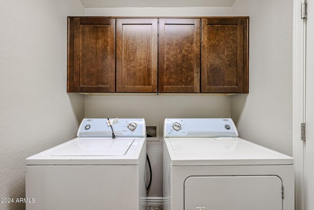 clothes washing area with cabinets and washer and clothes dryer