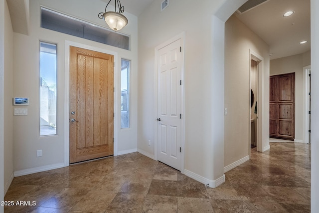 foyer with arched walkways, baseboards, recessed lighting, and visible vents