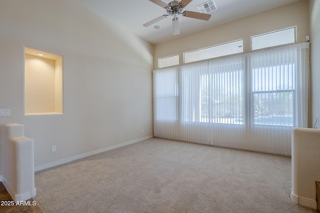 empty room featuring carpet floors, ceiling fan, visible vents, and plenty of natural light