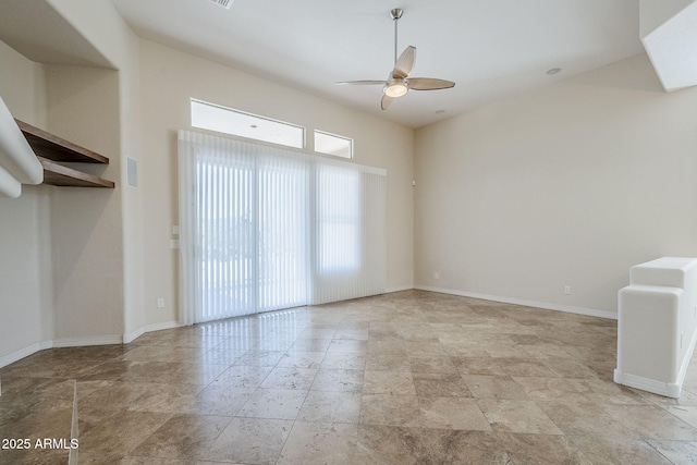 unfurnished living room featuring baseboards, ceiling fan, and stone finish flooring