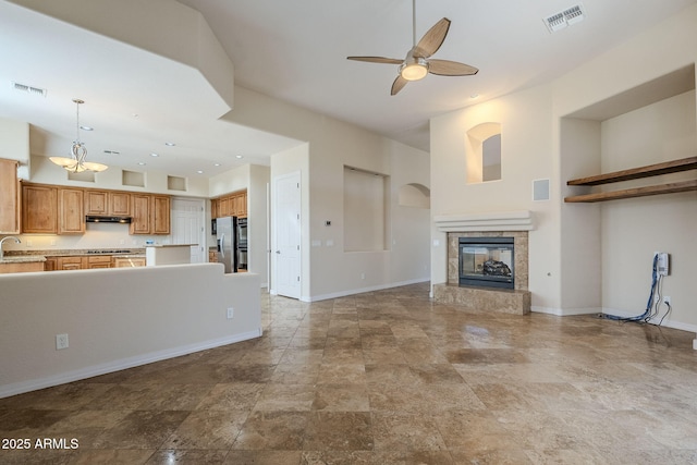 unfurnished living room featuring visible vents, a ceiling fan, a sink, and baseboards