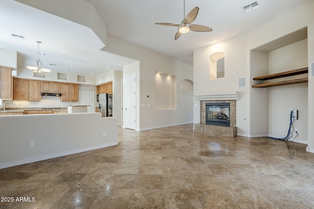unfurnished living room featuring visible vents, a ceiling fan, a sink, and a premium fireplace