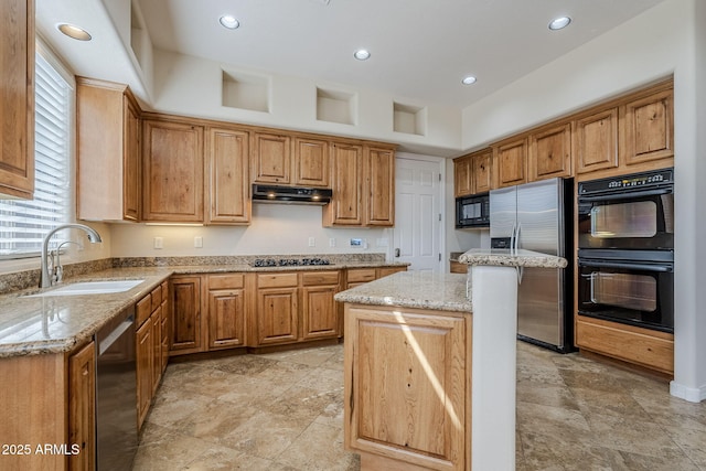 kitchen with a kitchen island, light stone countertops, a sink, black appliances, and under cabinet range hood
