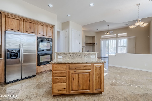 kitchen with dobule oven black, stainless steel refrigerator with ice dispenser, a center island, light stone countertops, and ceiling fan with notable chandelier