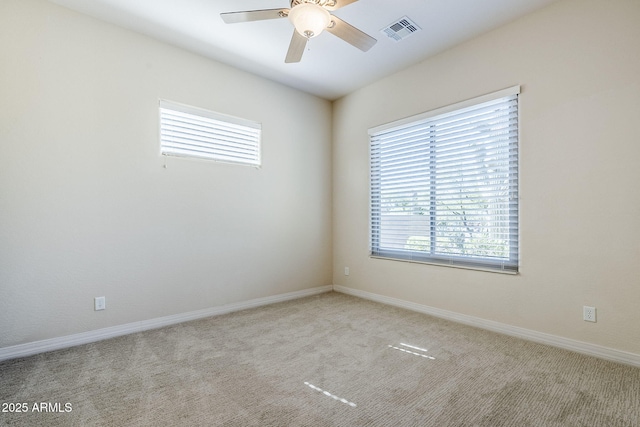 empty room with visible vents, a ceiling fan, carpet, and a wealth of natural light