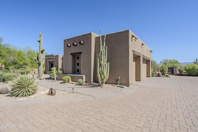 view of front of property featuring decorative driveway, a garage, and stucco siding