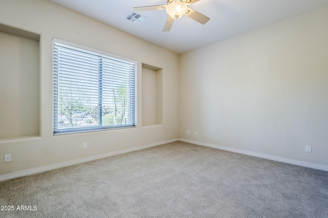 empty room with baseboards, ceiling fan, carpet, and visible vents
