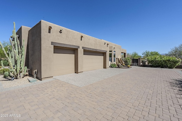view of front of home with a garage, stucco siding, and decorative driveway