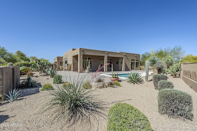 rear view of house featuring a fenced in pool, fence, a patio, and stucco siding