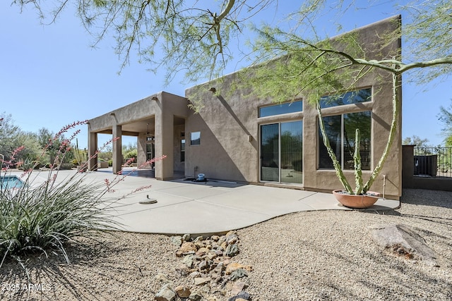 rear view of property featuring fence, a patio, and stucco siding