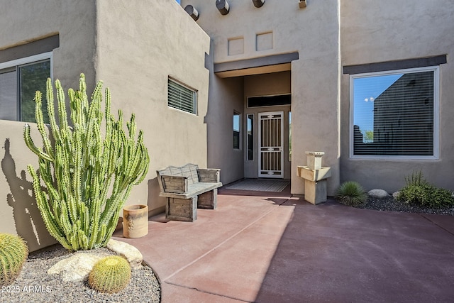view of exterior entry with a patio area and stucco siding