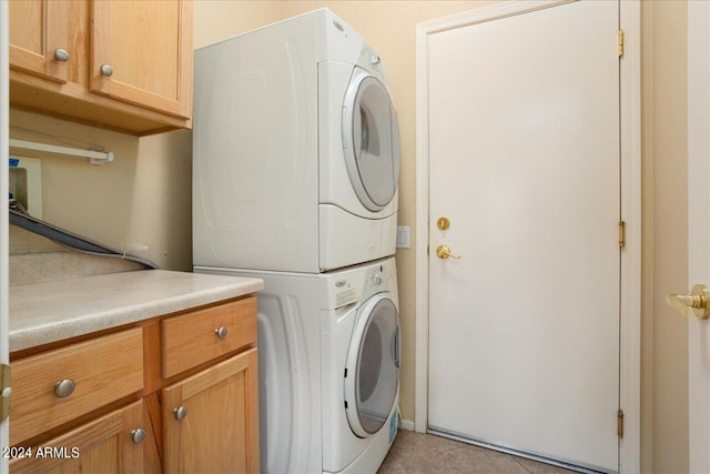 washroom with cabinets, light tile patterned floors, and stacked washing maching and dryer