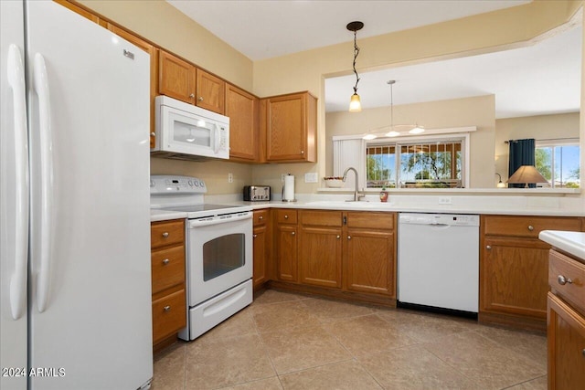 kitchen with hanging light fixtures, white appliances, sink, and light tile patterned floors