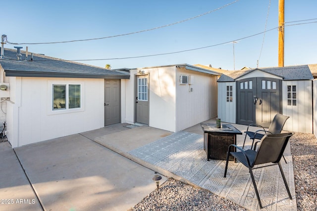 back of house with an outdoor fire pit, a patio area, and a storage unit