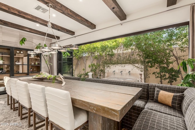 exterior space featuring an inviting chandelier and beam ceiling