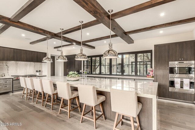 kitchen featuring a spacious island, decorative light fixtures, a breakfast bar, and double oven