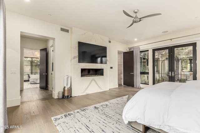 bedroom with hardwood / wood-style flooring, a premium fireplace, access to exterior, and french doors