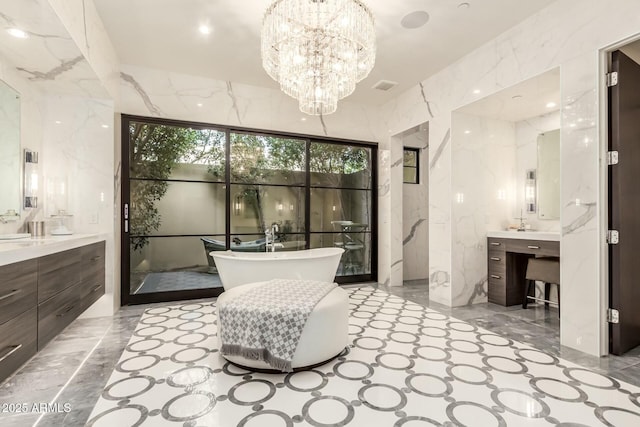 bathroom with an inviting chandelier, vanity, tile walls, and a tub