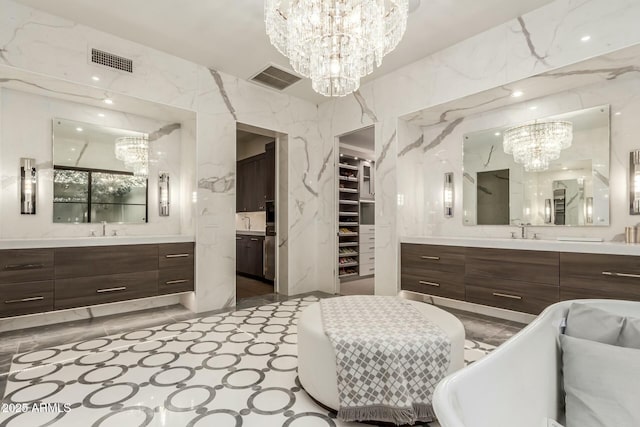 bathroom with an inviting chandelier, a bath, vanity, and tile walls