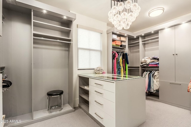 walk in closet featuring light colored carpet and a notable chandelier