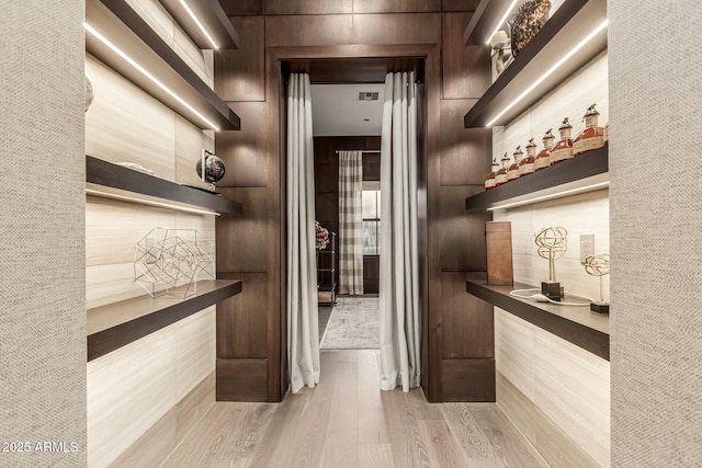 bar featuring dark brown cabinets and light hardwood / wood-style floors