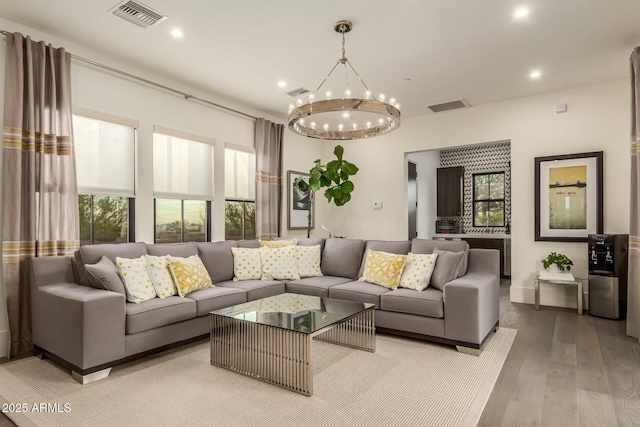 living room featuring an inviting chandelier, light wood-type flooring, and a wealth of natural light