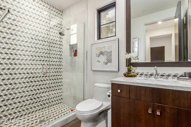 bathroom with a shower with door, vanity, decorative backsplash, and toilet