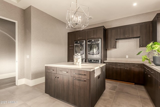 kitchen featuring dark brown cabinetry, decorative light fixtures, stainless steel oven, and stacked washer / dryer