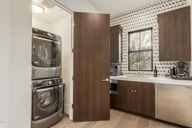 laundry room featuring sink, light hardwood / wood-style floors, and stacked washer / dryer