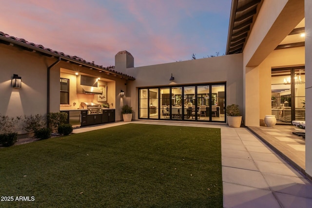 back house at dusk featuring area for grilling, a yard, and a patio area