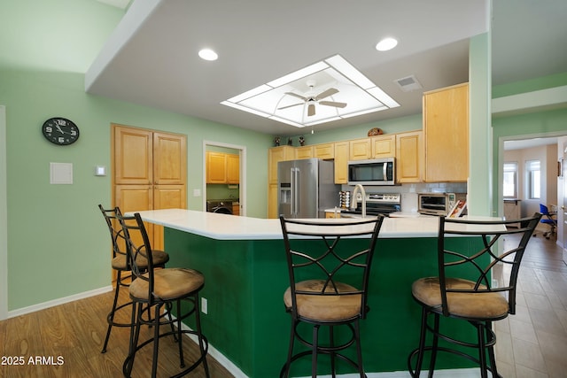 5830 E Mckellips Rd Unit 2, Mesa, AZ 85215 - kitchen featuring appliances with stainless steel finishes, light brown cabinets, a kitchen breakfast bar, a skylight, and a peninsula