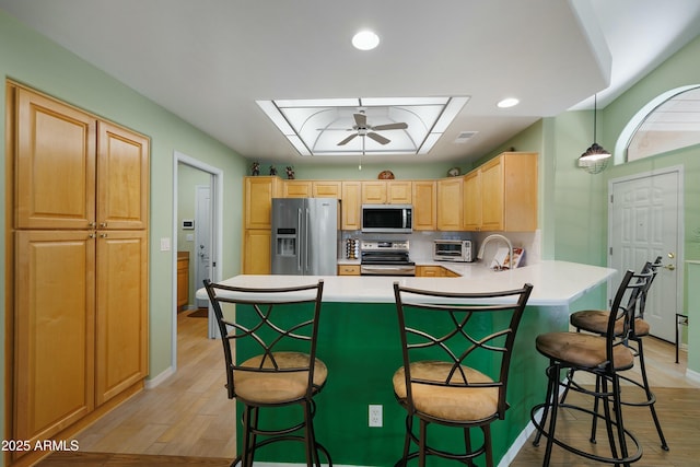 5830 E Mckellips Rd Unit 2, Mesa, AZ 85215 - kitchen with stainless steel appliances, a peninsula, light brown cabinets, a kitchen bar, and light countertops