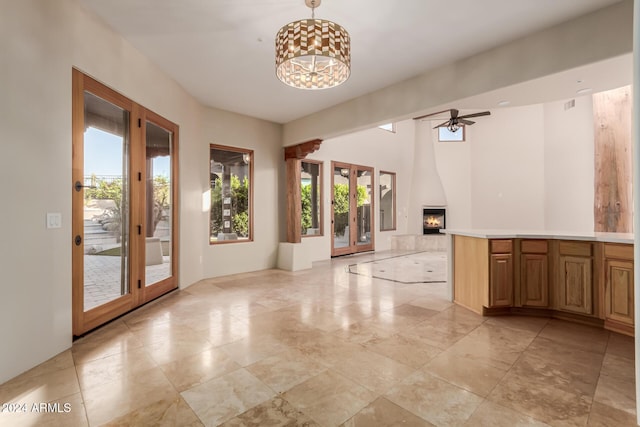 interior space featuring a large fireplace, ceiling fan, plenty of natural light, and french doors