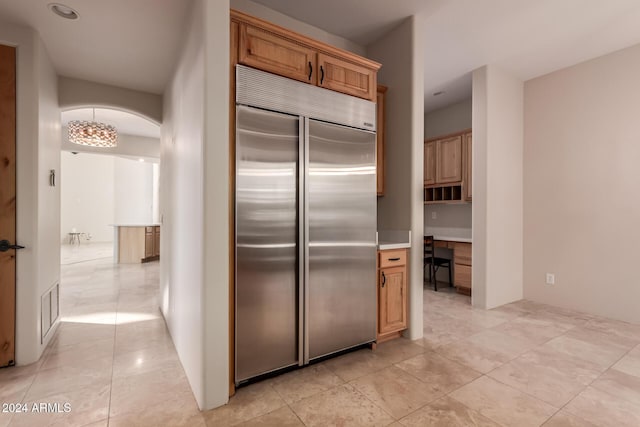 kitchen with stainless steel built in refrigerator, light tile patterned floors, and built in desk