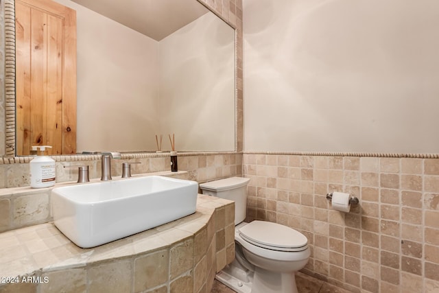 bathroom with sink, tile walls, and toilet