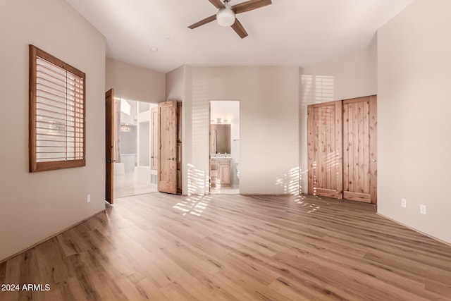 unfurnished bedroom with ensuite bath, ceiling fan, and light wood-type flooring