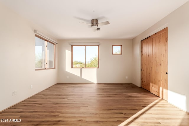 unfurnished bedroom featuring ceiling fan, a closet, and light wood-type flooring