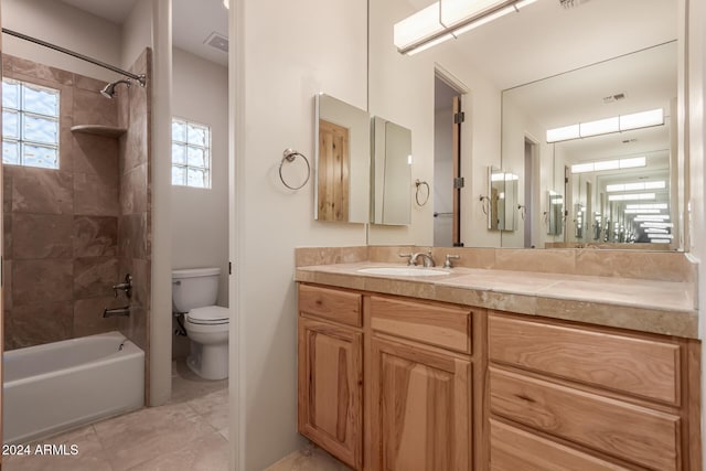 full bathroom featuring tile patterned flooring, tiled shower / bath combo, toilet, and vanity