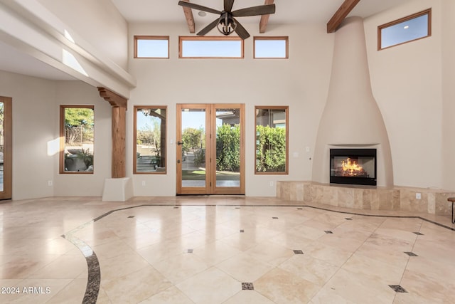 unfurnished living room with ceiling fan, beam ceiling, light tile patterned flooring, and a fireplace