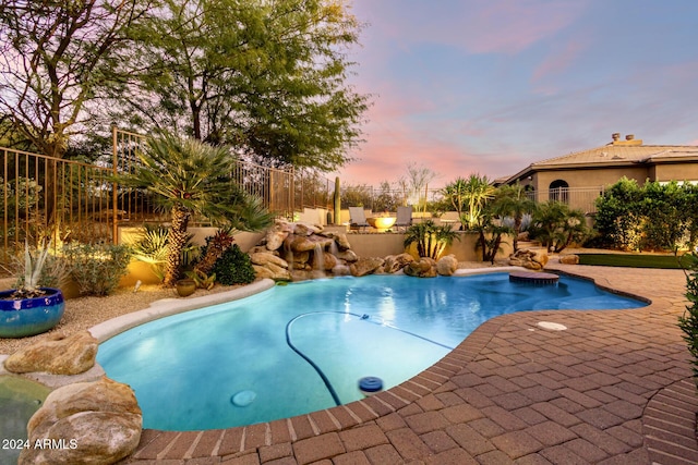 pool at dusk featuring a patio