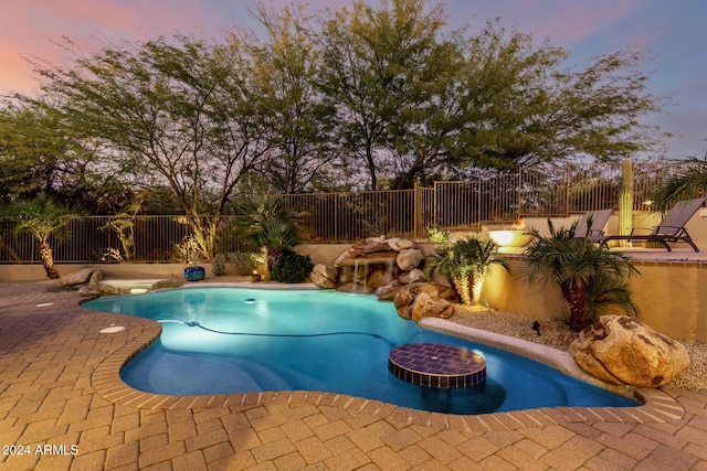 pool at dusk with a patio area