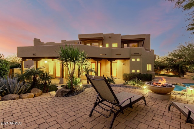 back house at dusk featuring a patio