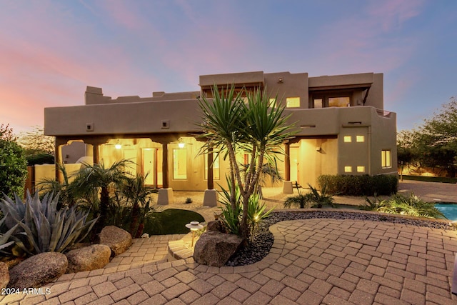 back house at dusk featuring a patio area